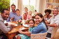 Family and friends sitting at a dining table, looking at camera