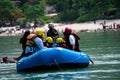 family friends sitting in raft enjoying adventure sports while crossing in front of ghat and temple on the banks of the