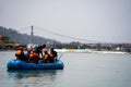 family friends in white water raft in front of temples ghats and the ram setu bridge in holy tourist town of rishikesh