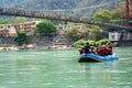 family friends in white water raft in front of temples ghats and the ram setu bridge in holy tourist town of rishikesh