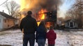Family in front of a burning house during a severe fire in winter. Generative AI Royalty Free Stock Photo
