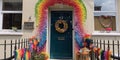 A family front door adorned with a welcoming pride-themed wreath, with children drawings of rainbows and hearts