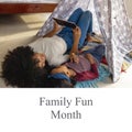 Family fun month text and biracial mother and daughter using digital tablet and lying at home Royalty Free Stock Photo