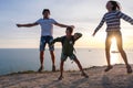 Family fun pastime on a mountain with seaside view. Dad, mom, and son jump at sunset. Side view Royalty Free Stock Photo