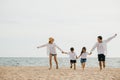 Family fun unfolds on beach parents holding hands running and jumping with their Royalty Free Stock Photo