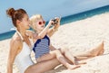 Happy mother and daughter in swimsuits taking photos at beach Royalty Free Stock Photo