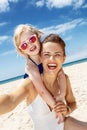 Mother and daughter in swimsuits taking selfies at beach Royalty Free Stock Photo