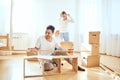 Father assembling furniture in living room of new apartment, mother with son and pile of moving boxes on background Royalty Free Stock Photo