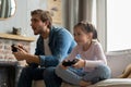 family, gaming and entertainment concept - happy father and little daughter with gamepads playing video game at home. Royalty Free Stock Photo