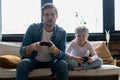 family, gaming and entertainment concept - happy father and little daughter with gamepads playing video game at home. Royalty Free Stock Photo