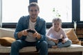 family, gaming and entertainment concept - happy father and little daughter with gamepads playing video game at home. Royalty Free Stock Photo