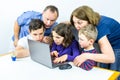 Family gathered around laptop looks at shocking content on internet, studio shot.