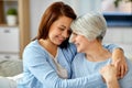 Senior mother with adult daughter hugging at home