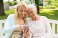 Daughter and senior mother with smartphone at park Royalty Free Stock Photo