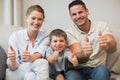 Family gesturing thumbs up on sofa Royalty Free Stock Photo