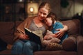 Family before going to bed mother reads to her child daughter book near a lamp in evening Royalty Free Stock Photo