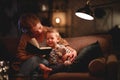 Family before going to bed mother reads to her child son book near a lamp in the evening