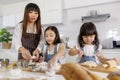 Family group photo of 30s mom teaching and educate two little girls, 3 years and 7 years old, how to make bread and bakery. They