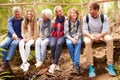 Family group sitting on a bridge in a forest, full length