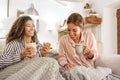 Family habits with diversity: multiracial homosexual female couple having fun at home sitting at the sofa drinking a cup of tea