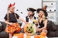 family in halloween costumes on sofa at coffee table with pumpkins Royalty Free Stock Photo