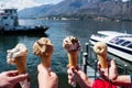 Family hands holding cones of Gelato, Italian ice-cream with blur background of a landscape view of Lake Como in Italy