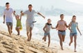 Family happily running together on beach Royalty Free Stock Photo