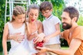 Family harvesting and eating cherries in garden