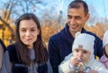 family has picnic in autumn city park, father and daughters, children and parent sitting together at the table, with apples and