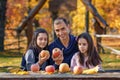 family has picnic in autumn city park, father and two daughters, children and parent sitting together at the table, with apples