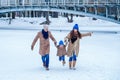 Family have fun on a frozen lake in the park against the background of the bridge Royalty Free Stock Photo