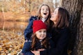 Family having fun in autumn park outdoors, hugging, laughing, relaxing, enjoy life. Adult mother embracing little daughters. Close Royalty Free Stock Photo