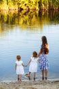 Family having fun together by the lake. Mother with her two daughters is on the walk next to the lake