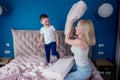 Family having fun together at the weekend together.Mother and child on bed. blonde mom and baby boy playing pillow fight Royalty Free Stock Photo