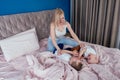 Family having fun together at the weekend together.Mother and two child on bed. blonde mom and baby boys playing in Royalty Free Stock Photo