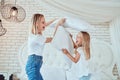 Family having funny pillow fight on bed. Beautiful mom with her little cute daughter spending free time together Royalty Free Stock Photo