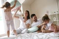 Family having funny pillow fight on bed.
