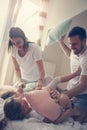 Family having funny pillow fight on bed.