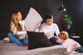 Family having funny pillow fight on bed. Parents spending free time with their son. Young family being playful at home Royalty Free Stock Photo