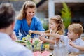 Family having garden party celebration, children are eating snacks, laughing and having fun.