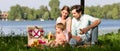Family having picnic at lake sitting on meadow Royalty Free Stock Photo