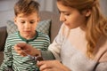 Mother giving medication or cough syrup to ill son