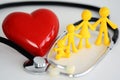 Family healthcare concept with plastic toys, red heart and stethoscope on white background