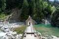 Family hiking across a wooden suspension bridge over the Rhine River in the Viamala Gorge in the Swis Alps Royalty Free Stock Photo