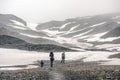 A family hiking up a snow field in the fog