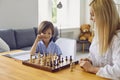 Family hobbies. Young mother playing chess with son at home. Little boy engaged in board game with his parent in room Royalty Free Stock Photo