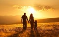 A family hold hands and walk in sunset on grassland with clouds shaped like love symbols above