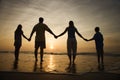 Family Holding Hands On Beach Watching The Sunset