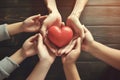 Family holding small red heart in hands on wooden background. Healthcare and hospital medical concept. Symbolic of Valentine day. Royalty Free Stock Photo