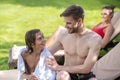 Father wrapping his son in towel, his wife resting on sun lounger